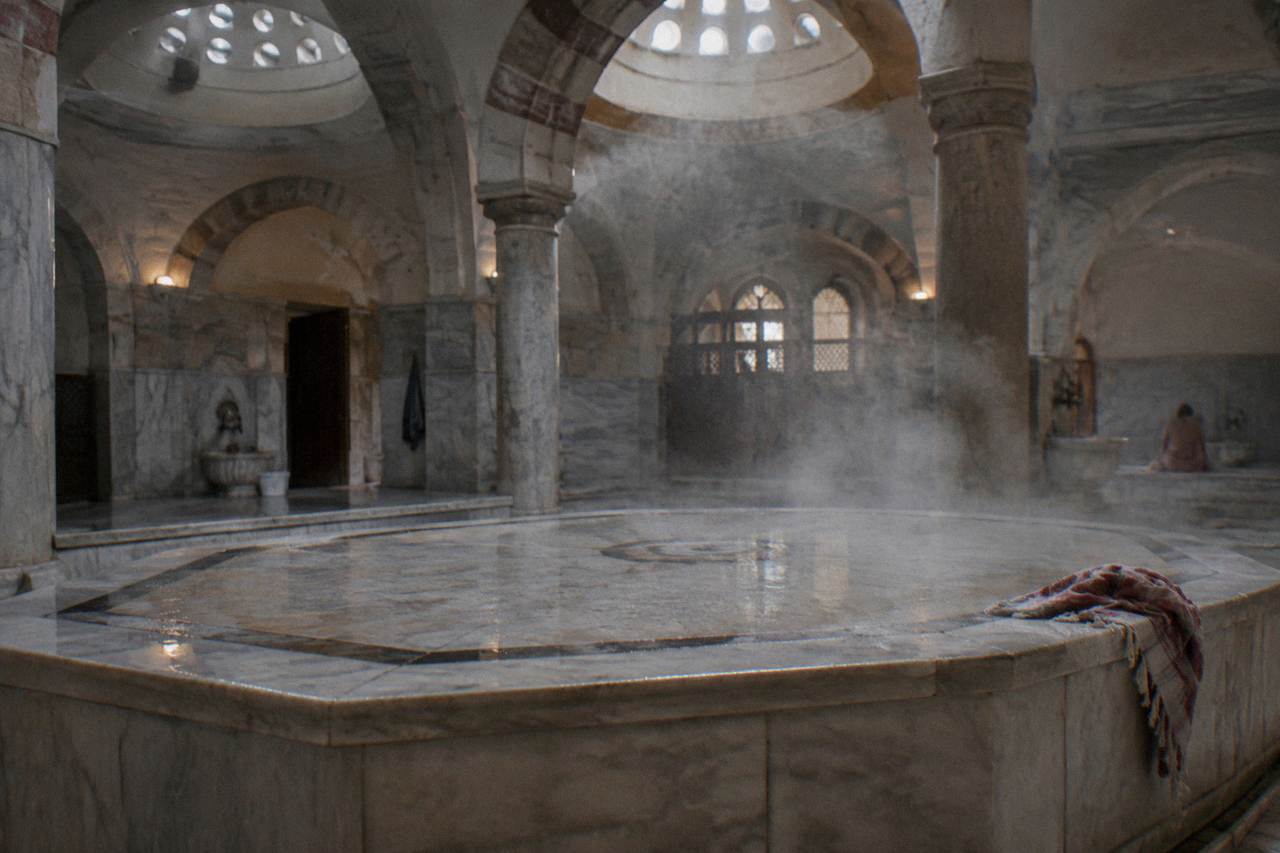 Steam rising over the heated marble platform inside a traditional Turkish bath hall