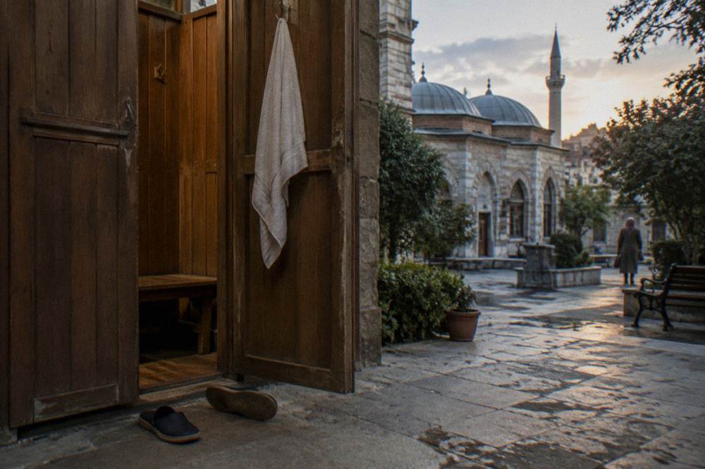 a wooden changing cabin with slippers on the floor and a towel hanging inside the door