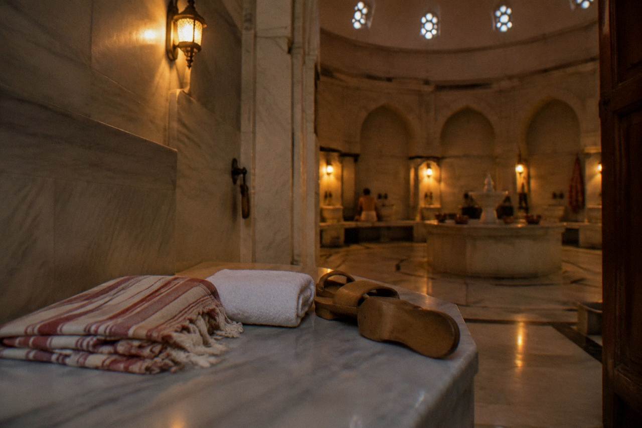 a folded striped peştemal, towel and slippers laid on a marble bench in a domed hamam changing cabin