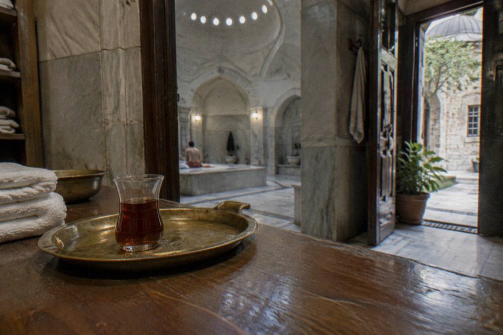 Wooden reception counter of a hamam with a brass tea tray and folded towels