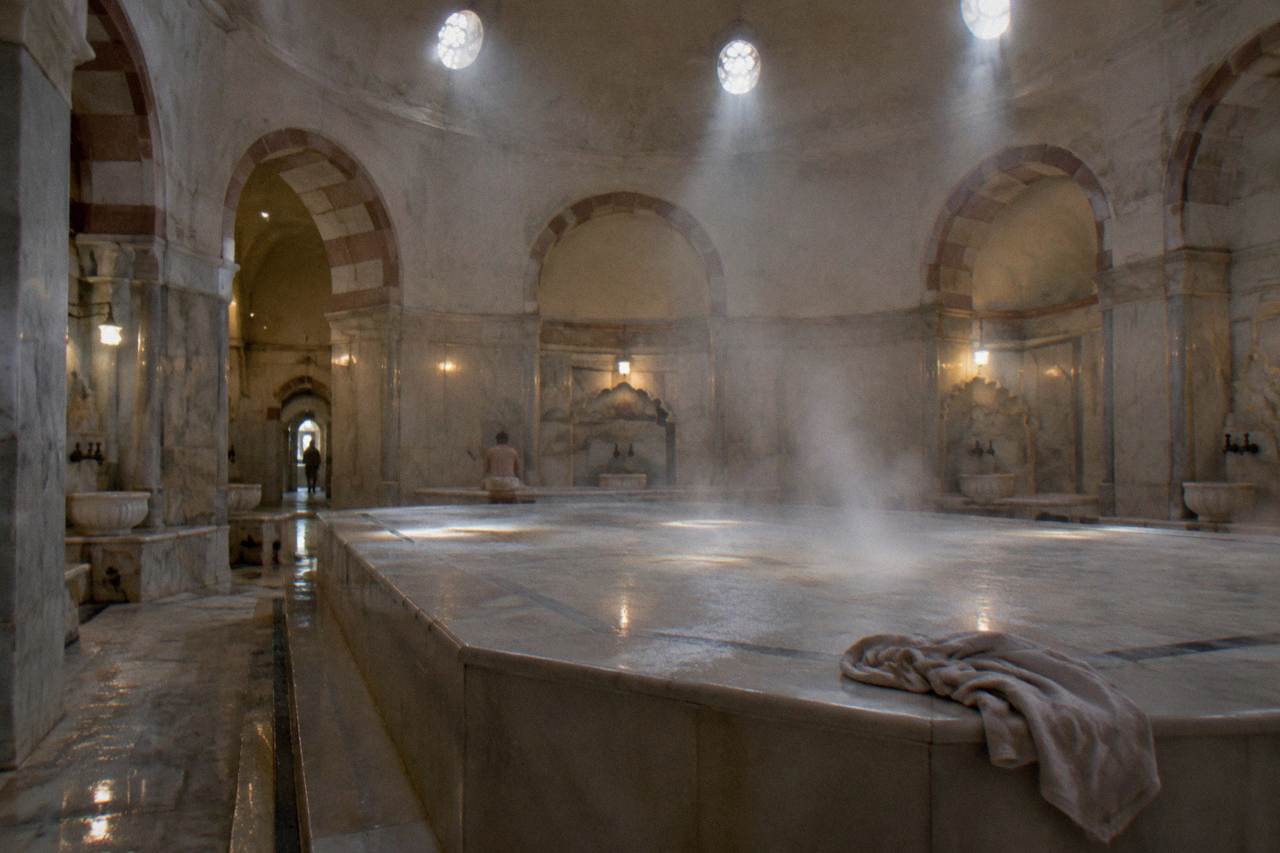 Warm domed hammam hall with a heated marble platform and steam in the air