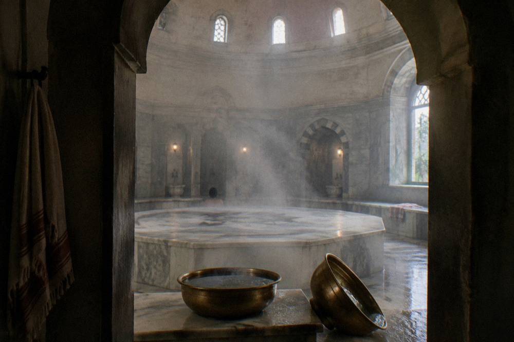Warm marble göbektaşı platform in an Ottoman bathhouse with brass basins along the wall