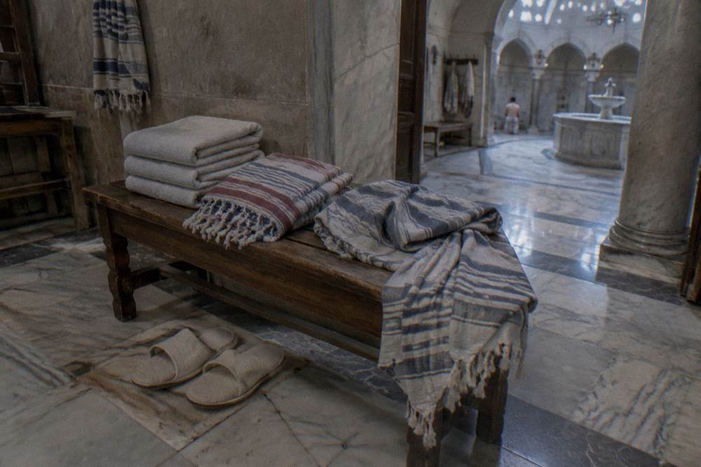 Folded peştemal wraps, towels and slippers arranged on a wooden hamam bench