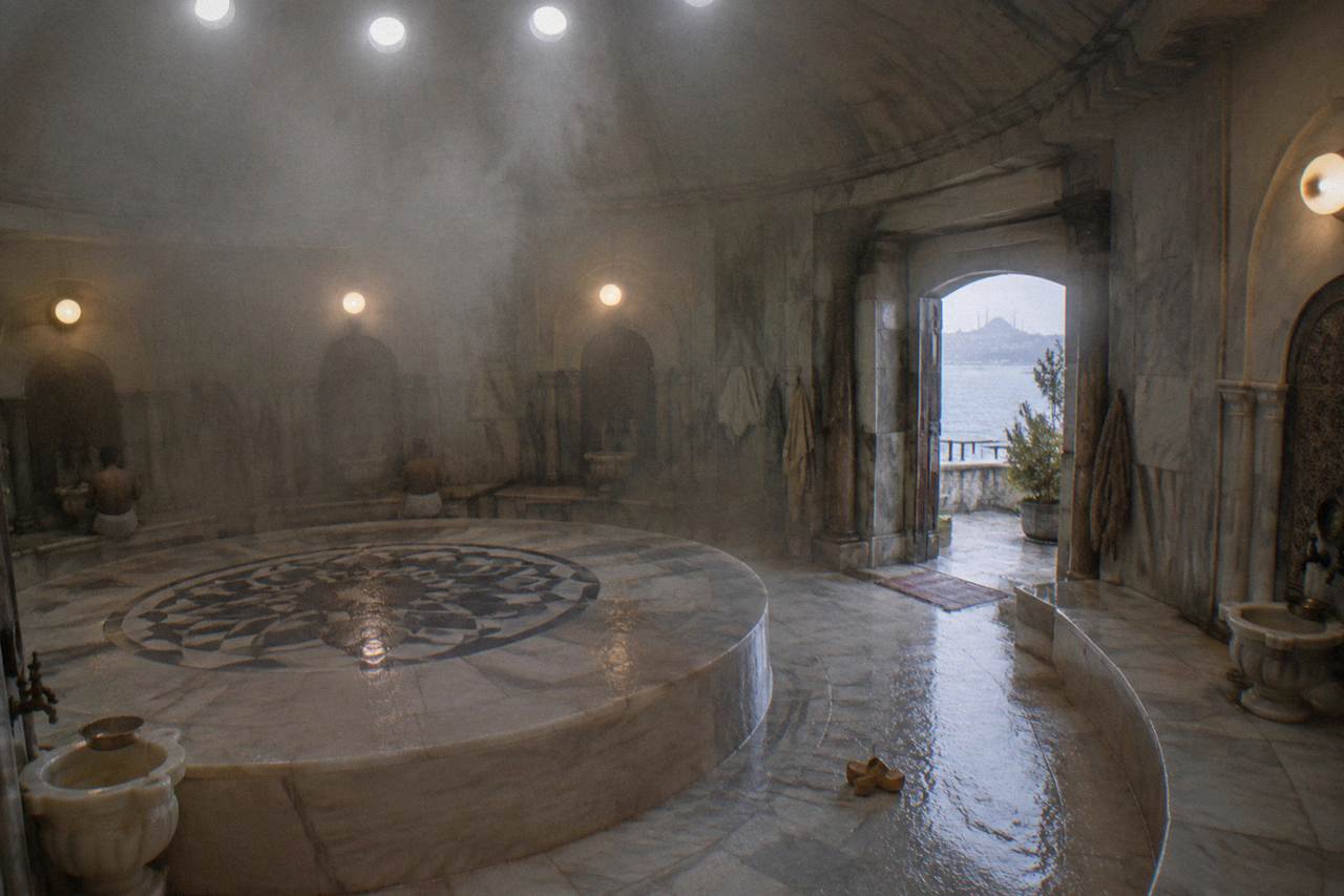 Domed marble hamam interior with steam rising past circular ceiling lights