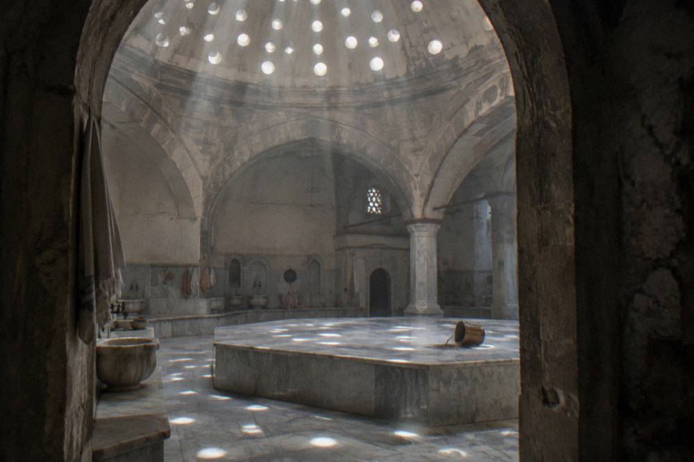 Ornate hamam domed ceiling with small glass eyelets casting light onto the stone floor