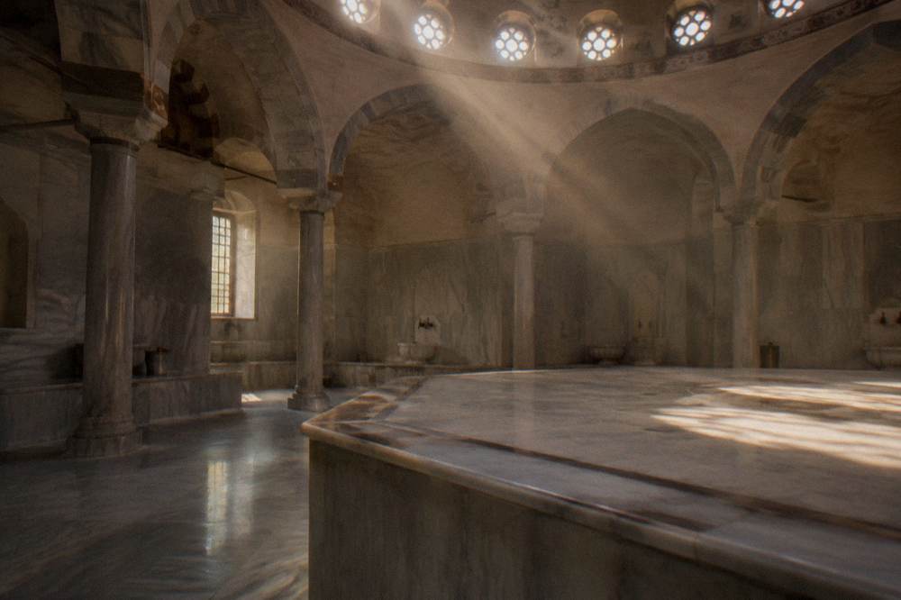 Sunlight through round dome windows falling on an empty marble hamam platform