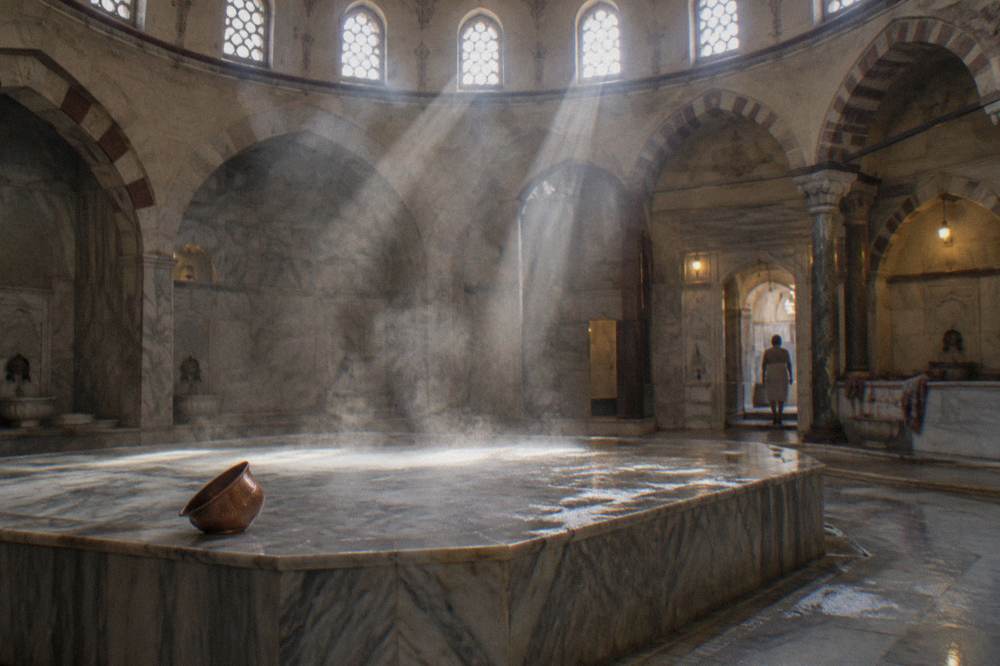 Steam rising through shafts of light over a heated marble platform in an empty hamam