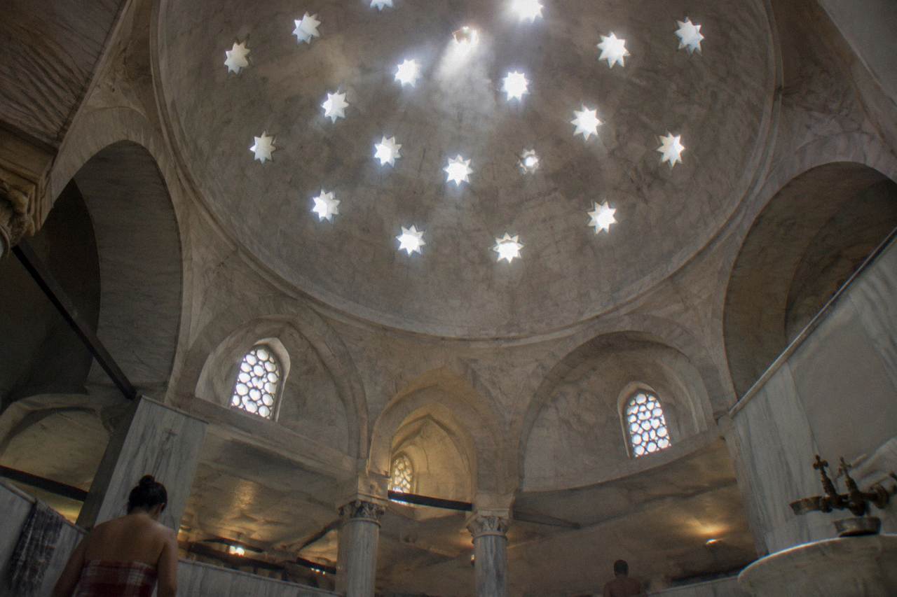 Domed ceiling with star shaped glass openings above the marble interior of a Turkish bath