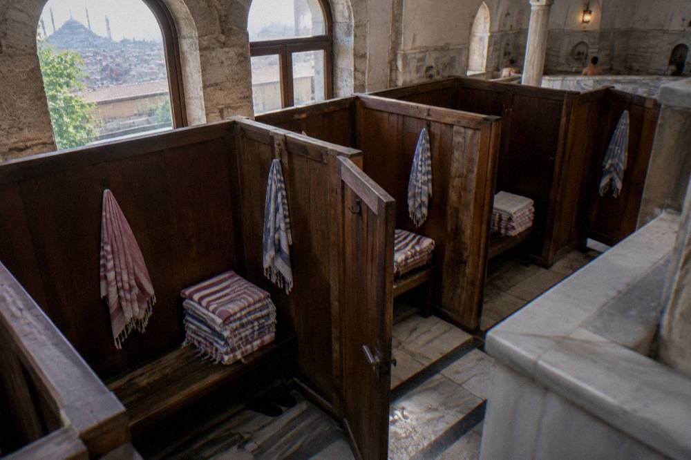 Stacked towels and folded cotton peştemal cloths on a wooden bench in a hamam changing area