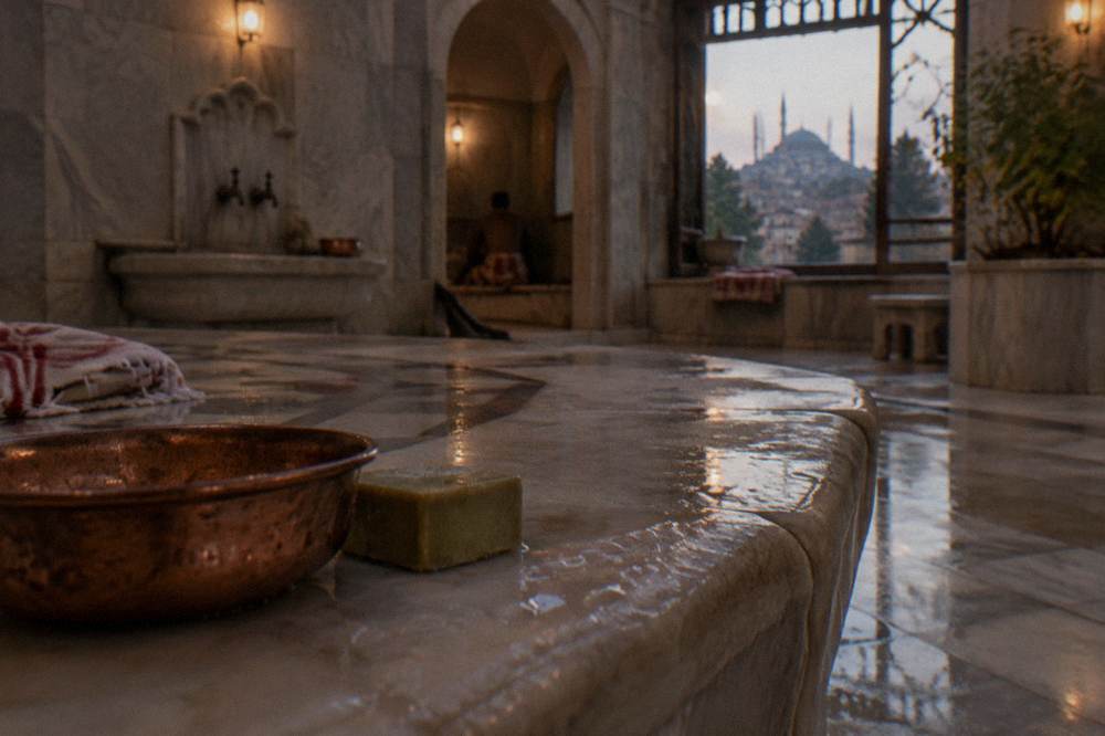 Copper hamam bowls and soap on the marble edge of a heated bathing platform