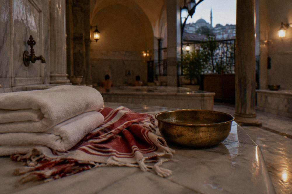Folded white towels and a striped woven peştemal laid on a marble bench