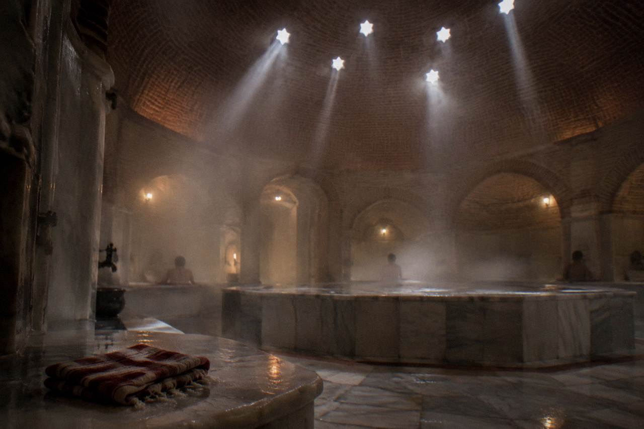 Steamy marble interior of an Ottoman bath under a stone dome with small glass lights