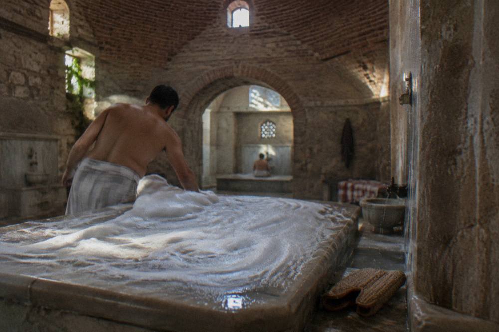 Warm marble hammam interior with steam rising from a heated stone slab