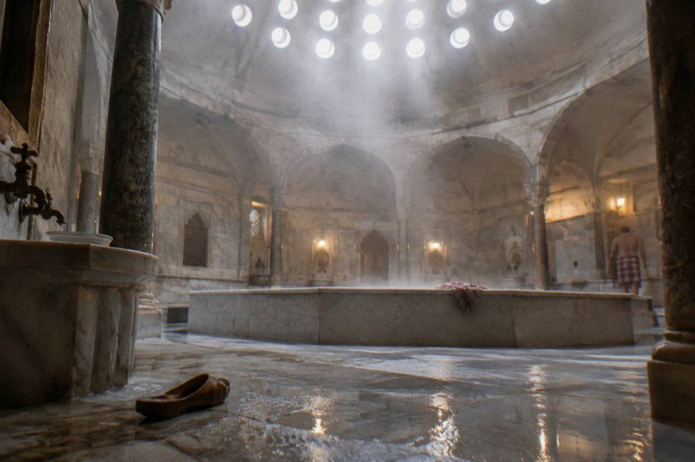 Steam rising in a hammam hot room with a domed ceiling pierced by round glass lights