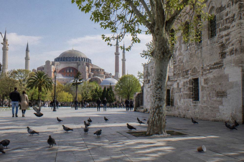 Exterior stone wall of an Ottoman bathhouse beside a tree in a historic city square