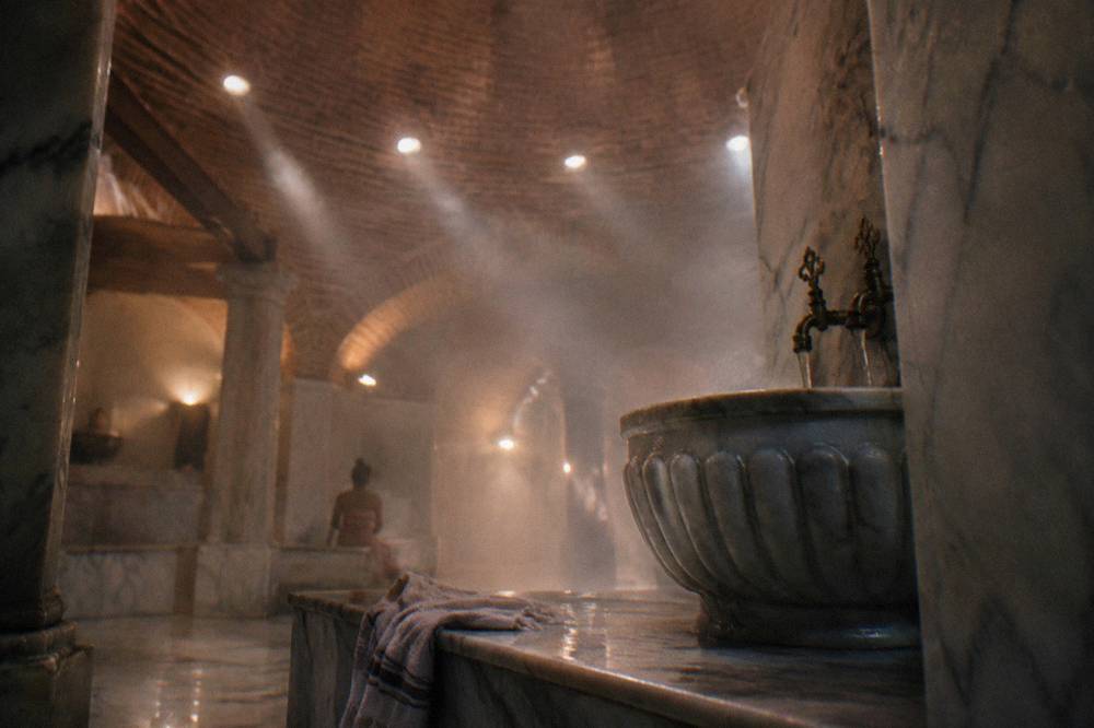 Domed hamam ceiling with small round glass lights casting beams through the steam