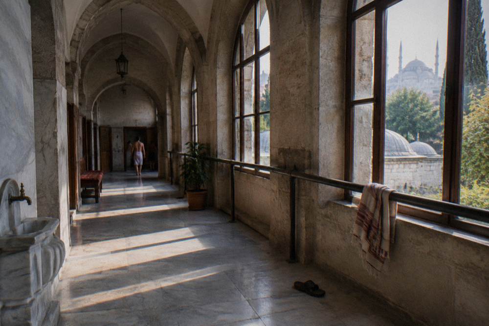 Tall arched windows along a quiet hamam corridor in soft morning light