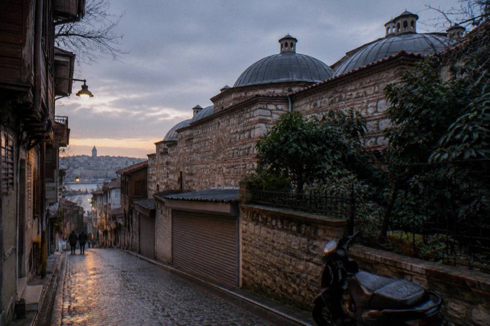 Exterior stone wall and small domes of an old bathhouse on a narrow city street in Istanbul