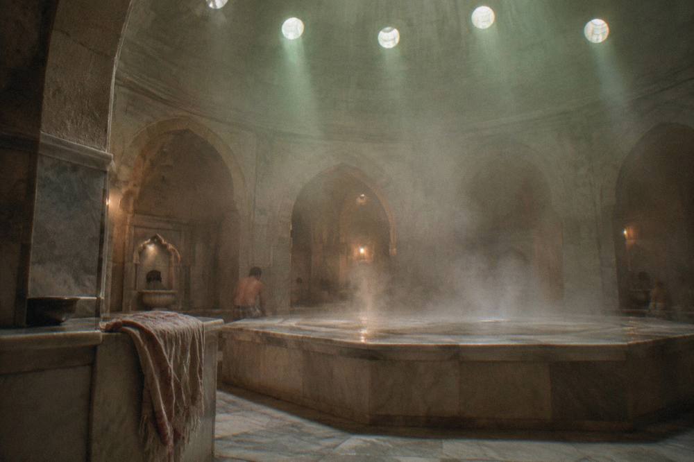 Steam rising from a hot marble platform in a domed hamam lit by skylights