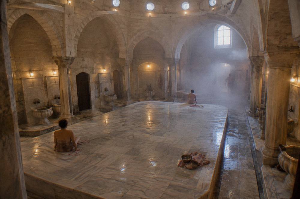 Warm marble interior of a Turkish bath with a raised stone platform and small domed lights