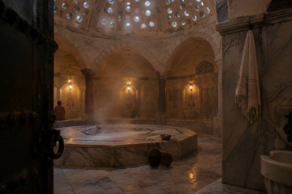 Warm marble interior of a historic Istanbul bath with a domed ceiling pierced by small glass circles