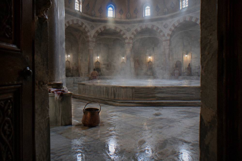 Warm marble interior of a historic Turkish bath with a raised stone platform and domed ceiling