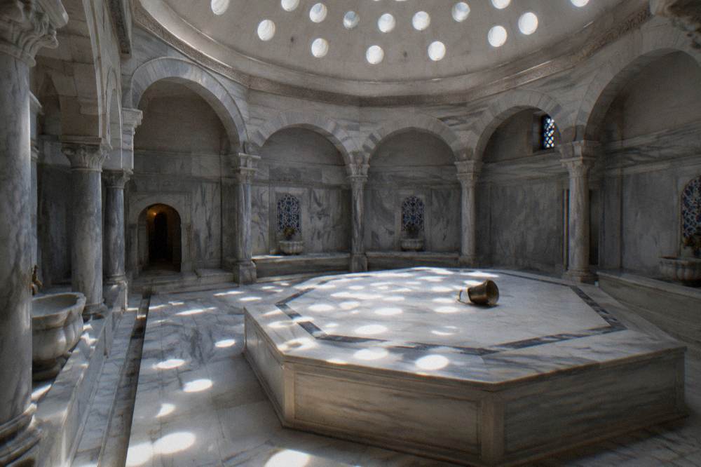 A stone hamam interior with domed ceiling and filtered daylight over an empty marble warming platform