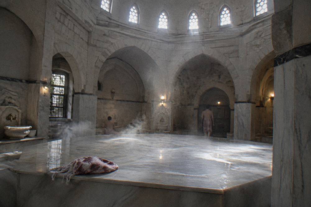 Steam rising from a hot marble platform under a domed hamam ceiling