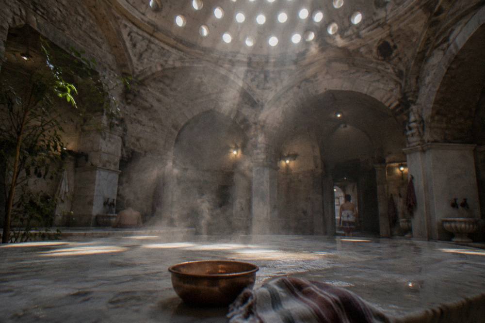 Steam rising from a hot marble platform beneath a pierced stone dome