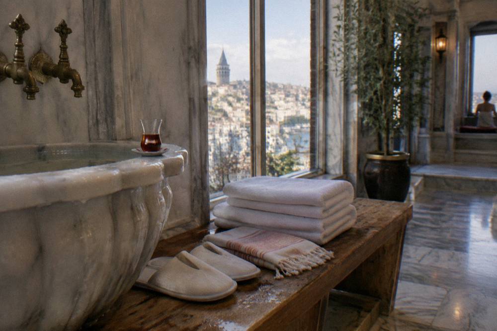 Folded towels, slippers and a breechcloth arranged on a wooden bench beside a hammam basin