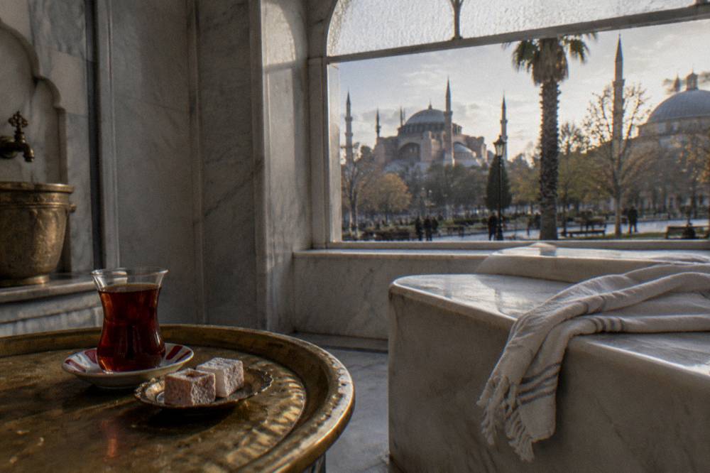 Glass of Turkish tea and small sweets on a tray beside a hammam resting bench