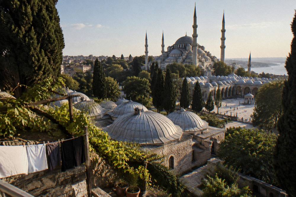 Grand Ottoman courtyard with a large domed mosque silhouette against the sky