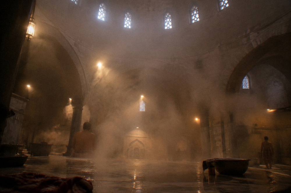 Rising steam drifting through shafts of light above a heated stone platform
