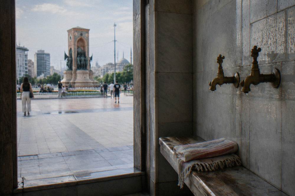 Tiled steam room alcove with brass taps and a folded cotton peştemal on a bench