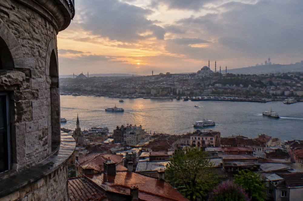 Dusk over Istanbul rooftops with the Süleymaniye skyline on one shore and the Beyoğlu hills beyond