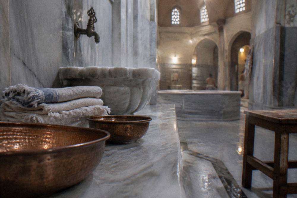 Copper bowls and stacked towels on a marble ledge inside a historic Istanbul hamam