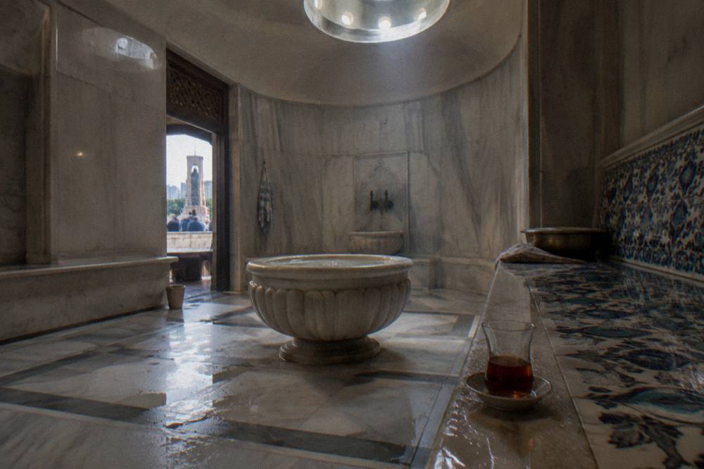Private hamam suite with a marble basin, a tiled bench and soft light from a dome above