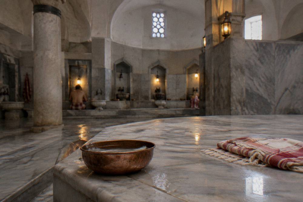 Warm marble göbektaşı platform in a lit traditional Turkish bath hall